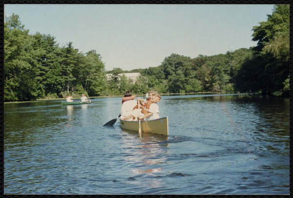 Children navigate canoes on a lake.